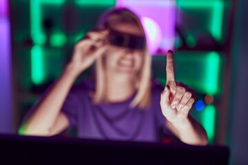 Canvas Print - Young blonde woman streamer using virtual reality glasses at gaming room