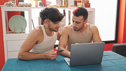 Canvas Print - Two men couple shopping with laptop and credit card sitting on table at dinning room