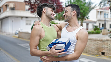 Poster - Two men couple smiling confident surprise with birthday gift at street