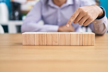 Sticker - Young hispanic man business worker sitting on table with wooden cubes at office