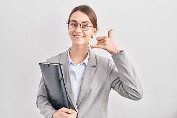 Sticker - Young caucasian woman wearing business clothes and glasses smiling doing phone gesture with hand and fingers like talking on the telephone. communicating concepts.