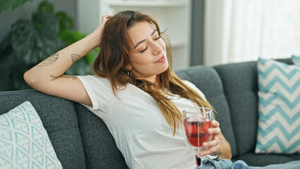 Wall Mural - Young beautiful hispanic woman drinking tea relaxed on sofa at home