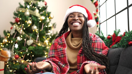 Wall Mural - African woman smiling sitting by christmas tree at home