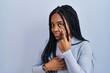 African american woman standing over blue background pointing to the eye watching you gesture, suspicious expression