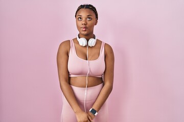 Canvas Print - African american woman with braids wearing sportswear and headphones making fish face with lips, crazy and comical gesture. funny expression.