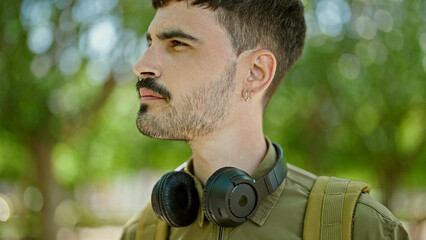 Wall Mural - Young hispanic man tourist wearing backpack and headphones at park