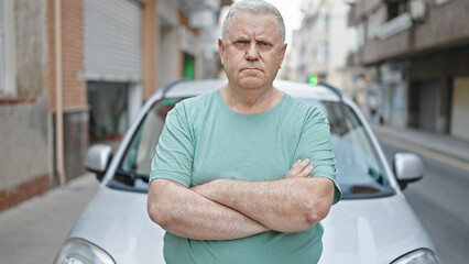 Wall Mural - Middle age grey-haired man standing by car with arms crossed gesture at street