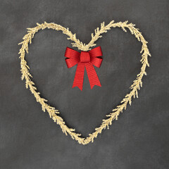 Wall Mural - Christmas gold tinsel heart shape wreath with red bow. Traditional romantic symbol for the festive holiday season on grunge gray background.