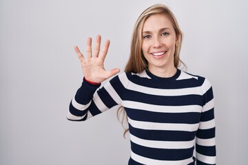 Wall Mural - Young caucasian woman wearing casual navy sweater showing and pointing up with fingers number five while smiling confident and happy.