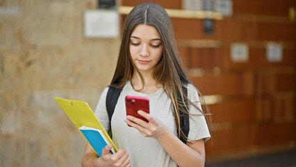 Canvas Print - Young beautiful girl student using smartphone with serious face at school