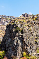 Poster - cliff with caves in river gorge near Geghard in Armenia on sunny autumn day