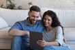 © fizkes - Happy husband and wife sharing tablet computer, enjoying online Internet communication, using app for shopping, booking, ordering, talking on video call, smiling, laughing, holding gadget