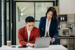 © laddawan - Asian business colleague business presents and explains and using laptop and tablet. Teamwork, financial marketing team,   while sitting in modern office