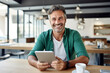 © Georgii - Cheerful Caucasian middle-aged man in casual clothes holding a tablet sits at table in cafe. Happy smiling mature businessman, successful entrepreneur or employee works online. Remote work concept.