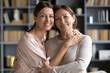 © fizkes - Family portrait, women relatives people daughter an elderly mother embracing standing close to each other smiling looking at camera, mom and adult child offspring, love and strong connection concept