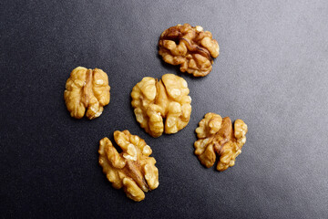Wall Mural - Top view of walnut seeds on dark background