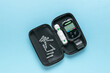 A blood glucose meter with a set of tests in a case on a blue background. The concept of getting rid of diseases.