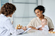 © AnnaStills - Young mother with child listening to doctor while sitting at table in her office