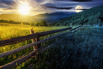 Wall Mural - rural landscape with sun and moon at twilight. fence near the meadow and trees on the hillside. day 