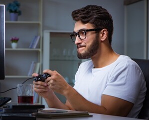 Wall Mural - Young man playing games long hours late in the office