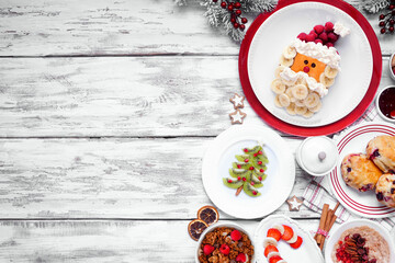 Aufkleber - Christmas breakfast side border. Overhead view on a white wood background. Fun holiday food concept. Santa pancakes, scones, fruit and cereals. Copy space.