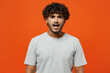 Young sad shocked astonished scared fearful Indian man he wearing t-shirt casual clothes looking camera with opened mouth isolated on orange red color background studio portrait. Lifestyle concept.