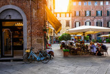 Fototapeta Uliczki - Old cozy street with tables of restaurant in Lucca, Italy