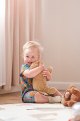 adorable little baby girl hugs a plush toy at home in a bright interior