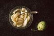 Birnenkompott, Birnen gekocht in einer Glasschüssel, Schale auf dunklem Hintergrund mit Tuch und roher Birne, Kompott, Dessert, Nachtisch. Draufsicht, Vogelperspektive