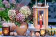 Arrangement mit Blumenstrauß mit Hortensienblüten und Hagebutten, Holzlaterne und Windlichtern 