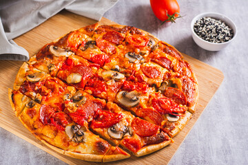 American St. Louis Style pizza with bacon, mushrooms and tomatoes on a board