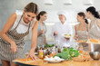 © JackF - Young woman in apron learns to cook chicken dish at cooking master class