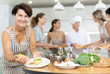 © JackF - Mature lady visiting culinary school completes preparation of tender dietary poultry meat and puts small amount of spicy sauce on fillet