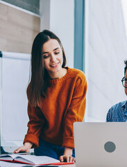 Wall Mural - positive smiling man and woman near working place with laptop cooperating in office