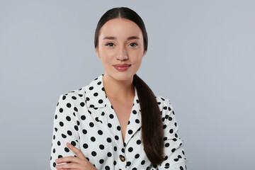 Poster - Portrait of beautiful young woman in polka dot blouse on light grey background