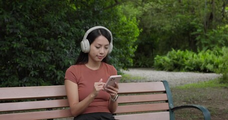 Poster - Woman listen to music on headphone and watch on cellphone