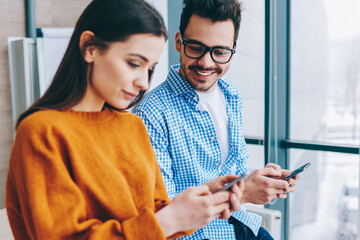 Wall Mural - positive millennial hipster guys using modern smartphones ignore real conversation