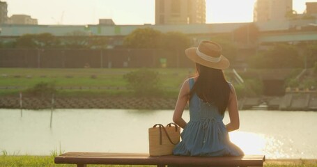 Wall Mural - Woman sit the bench under the sunset at river park