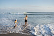 © Julija - Mother with daughter have fun at beach with black sand in Bali, running at waves, enjoy life and traveling