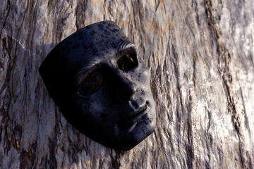 Selective focus black plastic mask placed on a beautifully patterned stone. give a strong feeling and has dark powers concept of the dark side of man There is space for text.