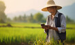 an old man farmer using mobile phone in rice field, smiling,Portrait of happy farmer holding rice grain whit smartphone.