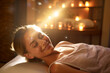 © toonsteb - a woman happily massaging shoulders in spa on a bokeh style background