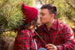 © farmuty - Bright sparklers against background of defocused couple in love at Christmas tree market. Man and woman laugh among green pine trees. Close-up portraits of happy lovers kissing at each other