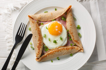 Canvas Print - Breton galette, galette sarrasin, buckwheat crepe, with fried egg, cheese, ham closeup on the plate on the table. Horizontal top view from above