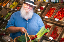 Senior Man Holding Basket Of Vegetables At Farmer's Market