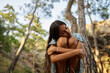 © Westend61 - Lonely teenage girl with eyes closed hugging knees in forest