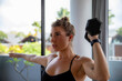 © Westend61 - Fit woman exercising with dumbbell at home