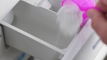 Close-up slow motion shot of hands pouring laundry household washing powder detergent laundry stain removal washroom clothing fragrance home living 4K