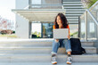 © Westend61 - Smiling student sitting with laptop on steps in campus