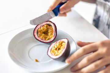 Wall Mural - A woman cuts a passion fruit into two halves.